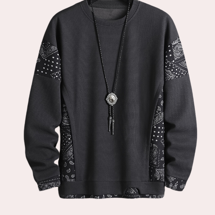 Donkergrijze trui met paisley-patroon en lange mouwen, versierd met een zwarte ketting. Stijlvolle herenkleding, casual streetwear.