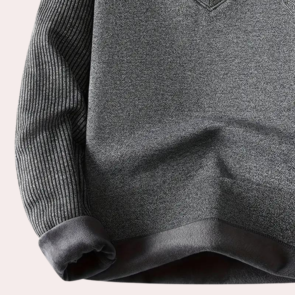 Grijze trui met geribbelde mouwen en borstzak, gemaakt van zachte stof. Ideaal voor casual herenkleding en herfstmode.