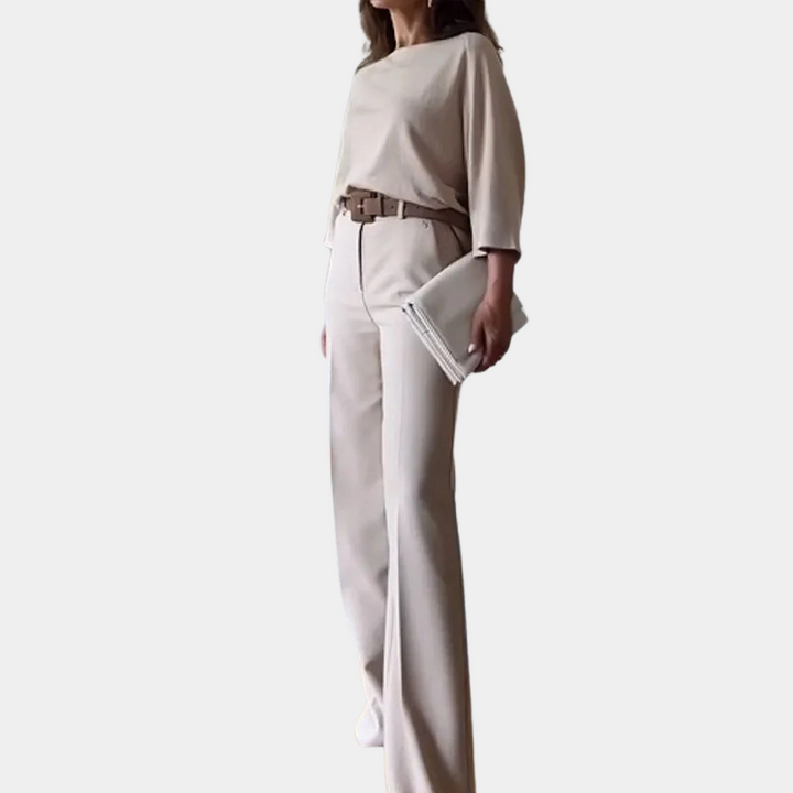 Dame in elegante beige outfit met wijde broek en blouse, bruine riem en witte clutch. Modieuze dameskleding, minimalistische stijl.