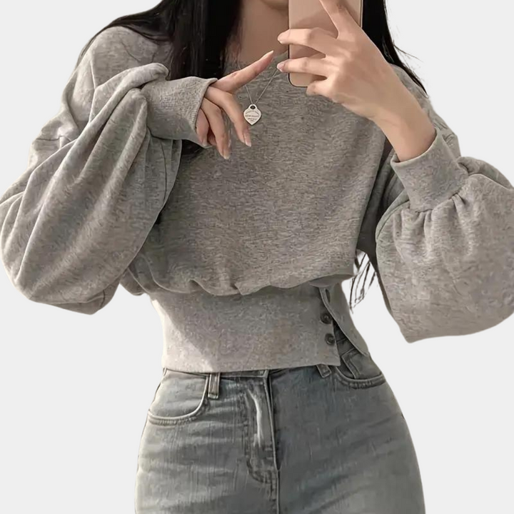 Grijze cropped trui met ballonmouwen, gedragen door model. Trendy damesmode, casual stijl, perfect voor herfst- en winteroutfits.