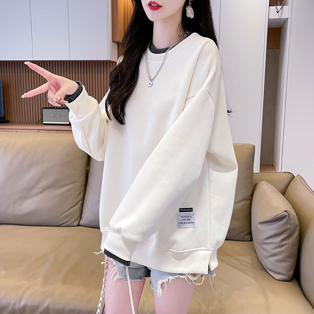 Vrouw in oversized crèmekleurige trui met grijze shorts, poseert in moderne woonkamer. Trendy casual outfit, comfortabele mode, herfststijl.