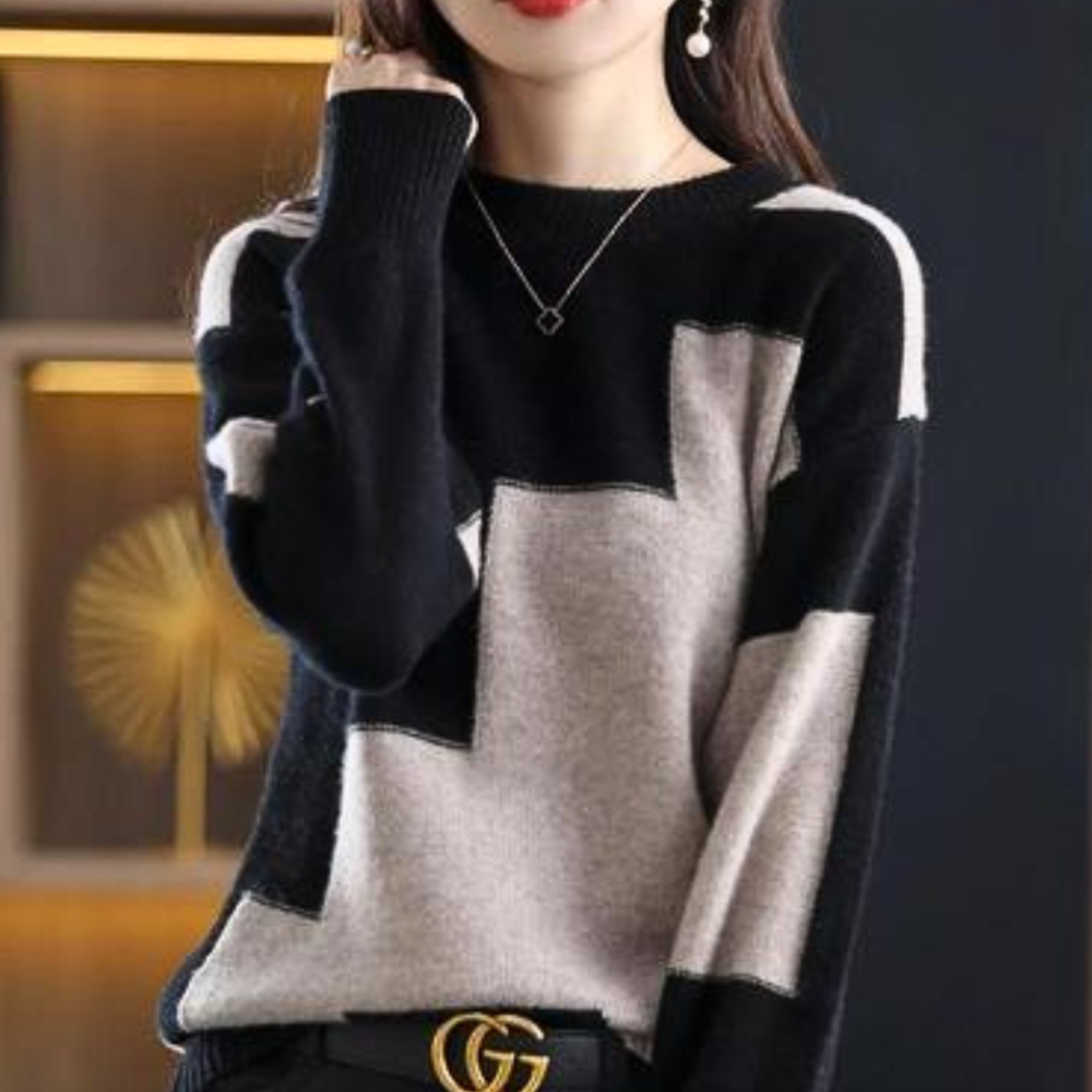 Vrouw in stijlvolle zwart-grijze trui met geometrisch patroon, gouden riem en oorbellen. Modieuze dameskleding, herfst-winter collectie.