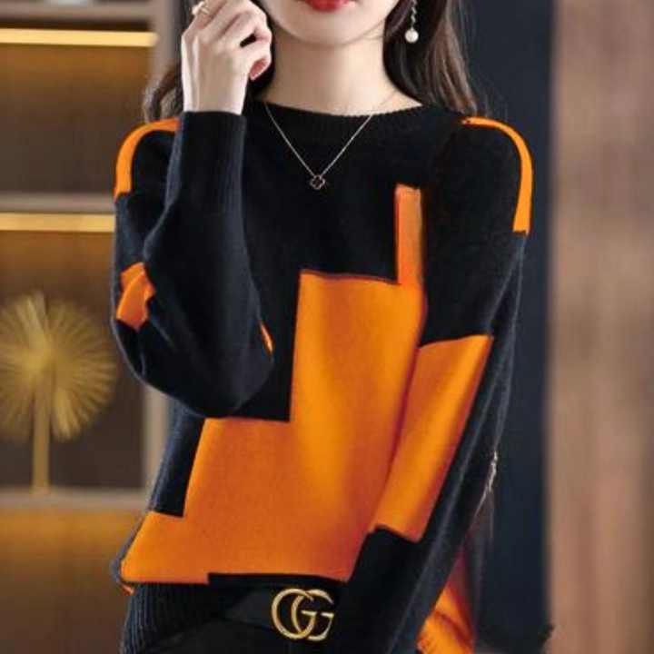 Vrouw draagt stijlvolle zwart-oranje trui met geometrisch patroon, gecombineerd met een gouden riem. Trendy herfstmode, dameskleding, casual chic.