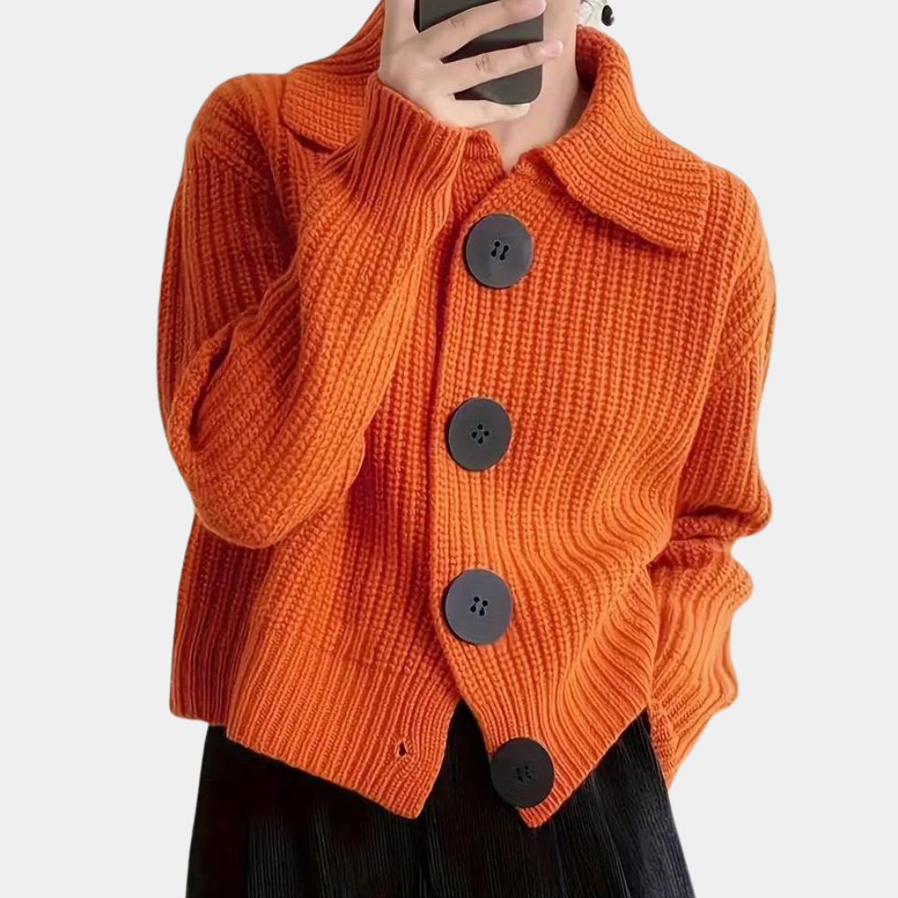 Oranje gebreid vest met grote zwarte knopen, gedragen door een persoon. Stijlvolle herfstmode, warme dameskleding, trendy en comfortabel.
