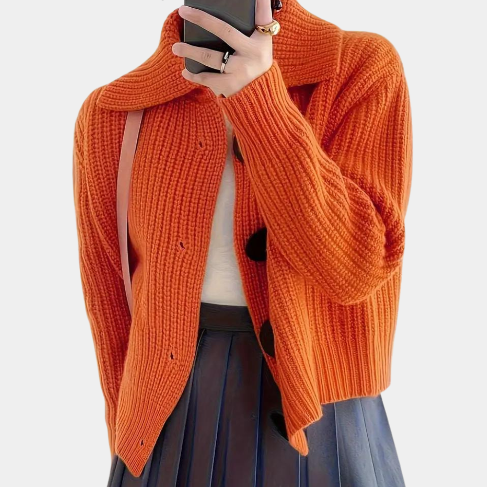 Oranje gebreid vest met grote knopen, gedragen door een persoon met een witte top en zwarte rok. Modieuze herfstkleding, damesmode, casual stijl.