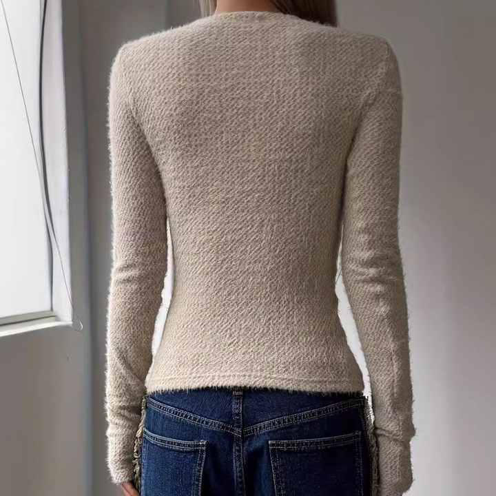 Beige gebreide damestrui met lange mouwen, getailleerd ontwerp, gedragen met blauwe jeans. Perfect voor casual herfst- en winteroutfits.