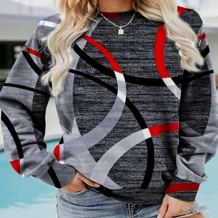 Grijze damestrui met abstracte rode, zwarte en witte cirkelpatronen, gedragen door model. Trendy herfstmode, casual stijl, comfortabele pasvorm.