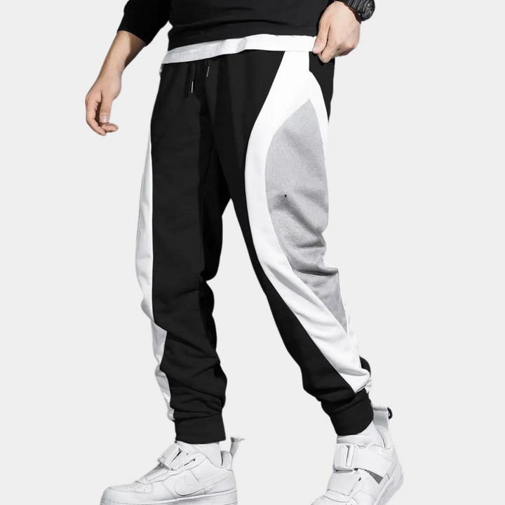 Zwart-witte joggingbroek met grijze accenten, gedragen door een man. Comfortabele sportkleding, ideaal voor casual en actieve outfits.