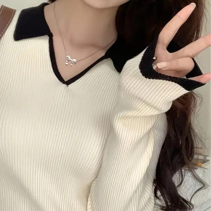 Vrouw draagt crèmekleurige trui met zwarte kraag en mouwdetails, modieuze kleding, herfstmode, stijlvolle dameskleding, trendy outfit.