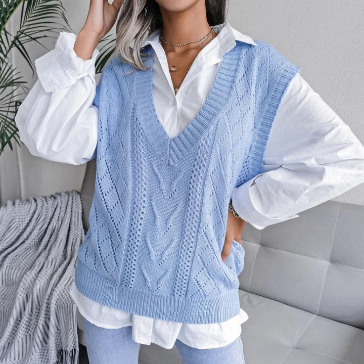 Vrouw draagt lichtblauwe gebreide spencer over witte blouse, casual chique outfit, trendy damesmode, comfortabele herfstkleding, stijlvolle look.