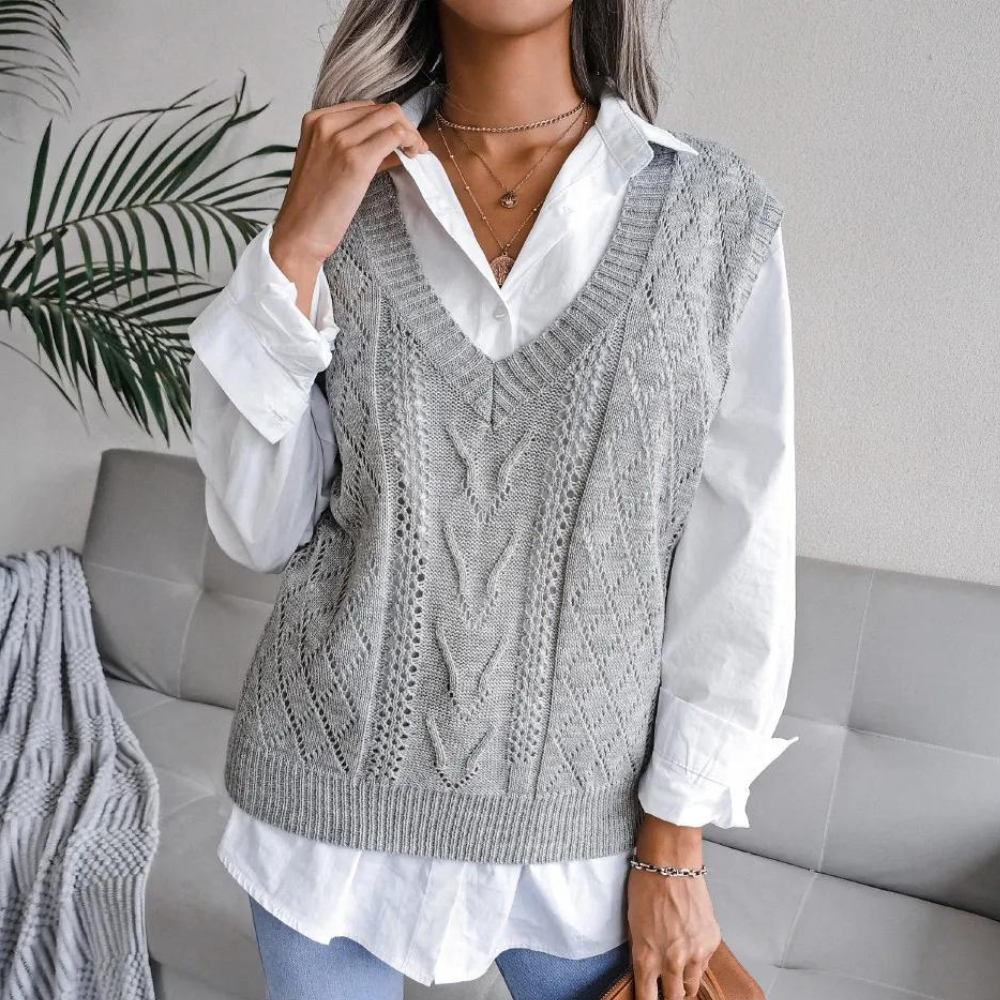 Grijze gebreide spencer met kabelpatroon, gedragen over een witte blouse. Trendy damesmode, casual chique stijl, perfect voor herfstoutfits.