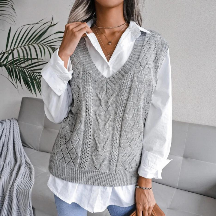 Grijze gebreide spencer met kabelpatroon, gedragen over een witte blouse. Trendy damesmode, casual chique stijl, perfect voor herfstoutfits.
