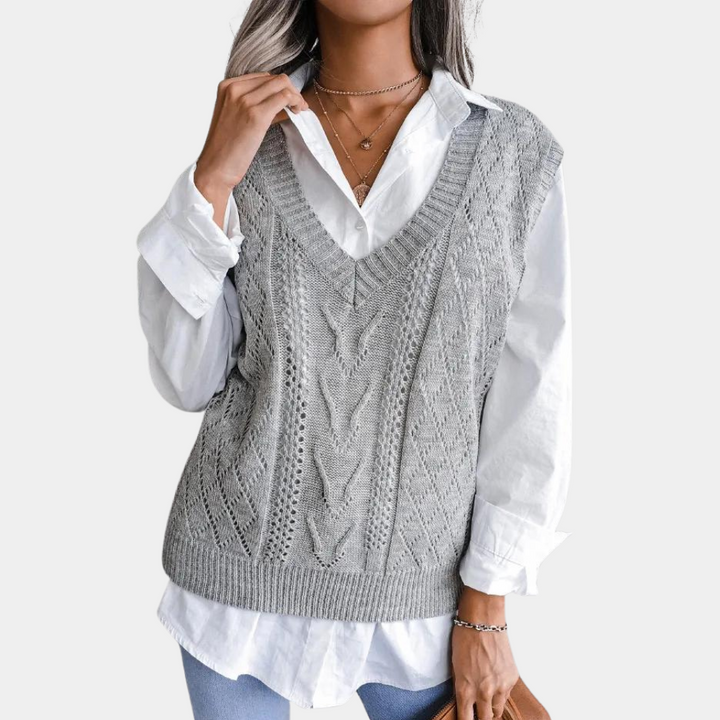 Grijze gebreide dames spencer met V-hals, gedragen over een witte blouse. Modieuze herfstkleding, perfect voor casual en stijlvolle outfits.