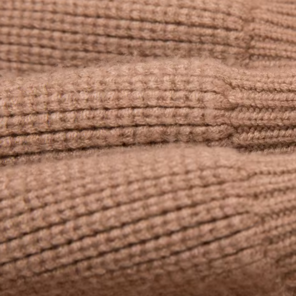 Close-up van beige gebreide stof met ribbelpatroon, ideaal voor warme truien en wintermode. Hoogwaardige textuur en zachte wolmix.
