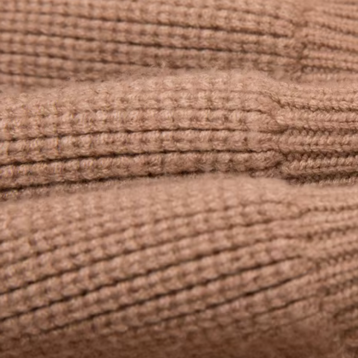 Close-up van beige gebreide stof met ribbelpatroon, ideaal voor warme truien en wintermode. Hoogwaardige textuur en zachte wolmix.