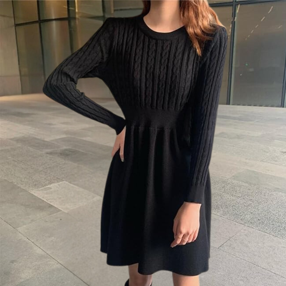 Vrouw in zwarte gebreide jurk met lange mouwen, staand in moderne stedelijke omgeving. Elegante damesmode, herfstkleding, casual chic stijl.