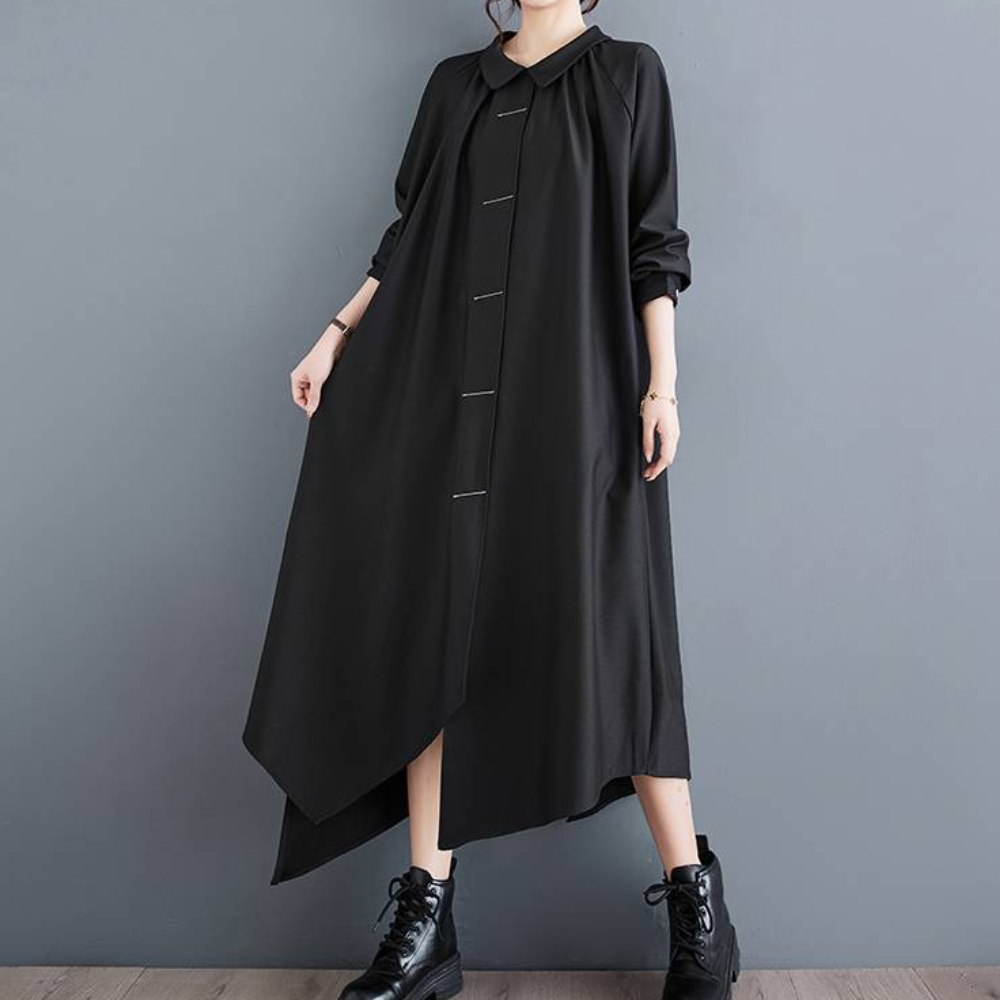 Zwarte asymmetrische maxi-jurk met lange mouwen en knoopsluiting, gedragen door model met zwarte veterlaarzen. Elegante damesmode.