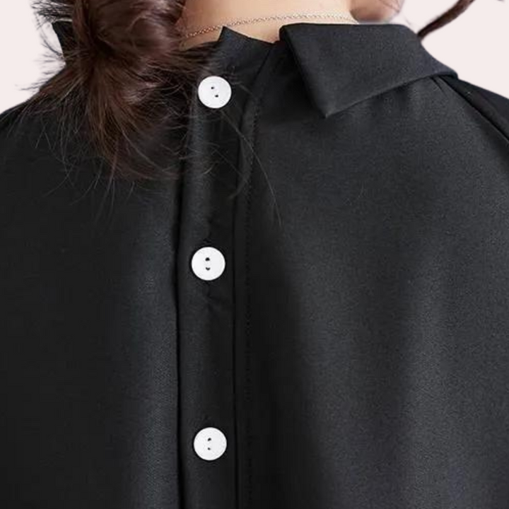 Zwarte blouse met witte knopen, close-up van de achterkant. Elegante damesmode, satijnachtige stof, stijlvolle kraag, trendy kledingstuk.