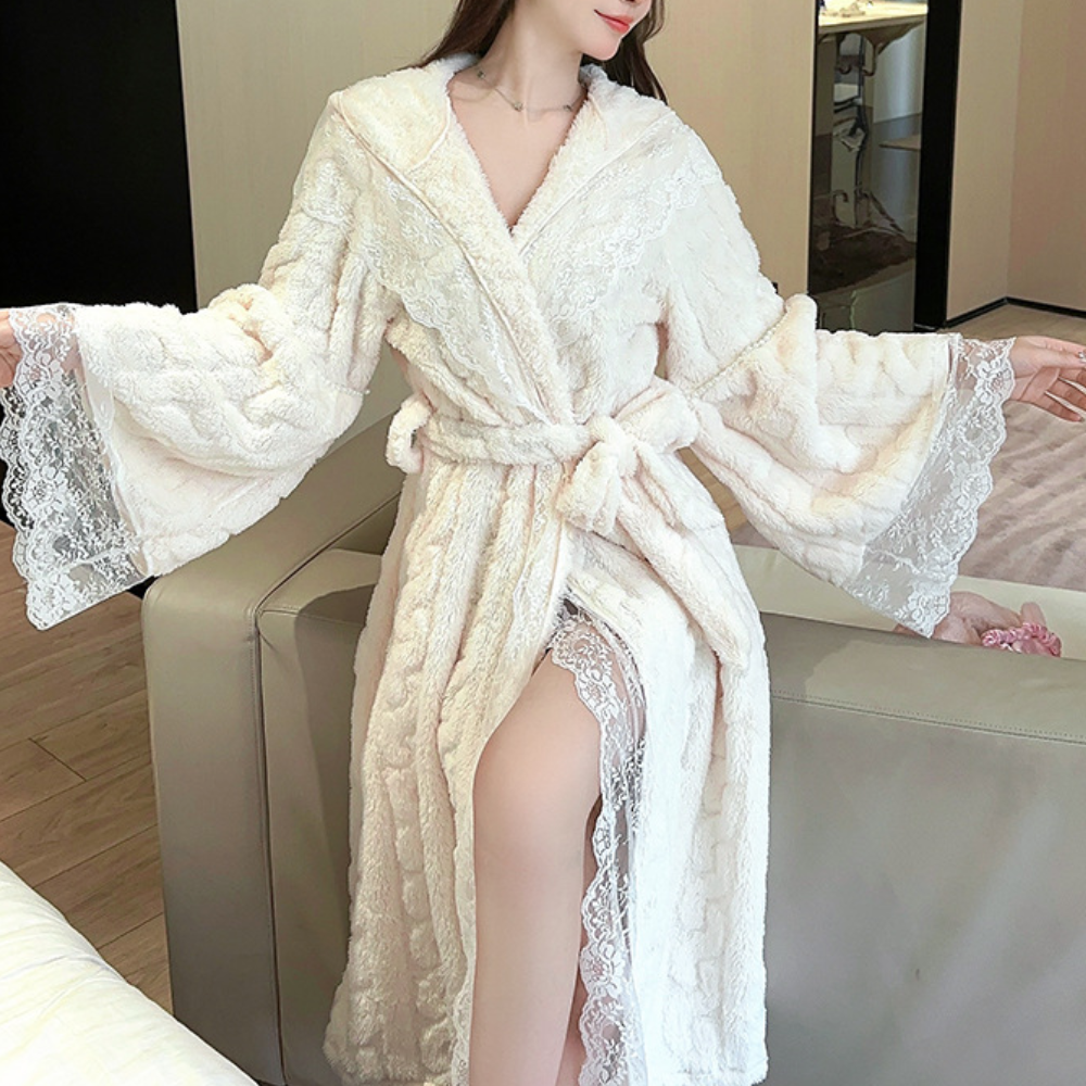Vrouw in luxe witte badjas met kant, zittend op een bank. Elegante ochtendjas, comfortabele loungewear, perfect voor thuisontspanning.