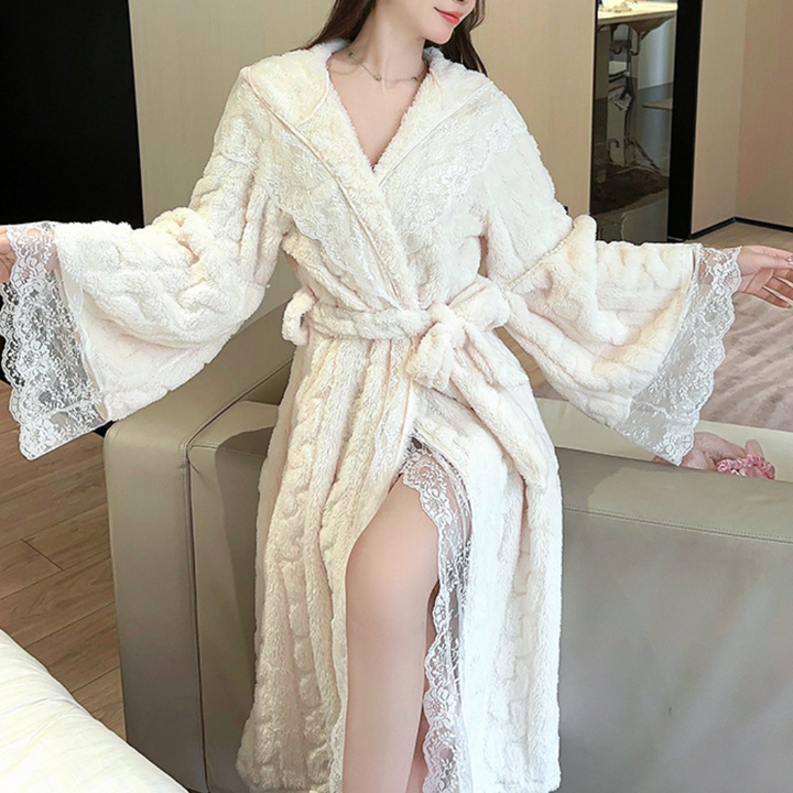 Vrouw in luxe witte badjas met kant, zittend op een bank. Elegante ochtendjas, comfortabele loungewear, perfect voor thuisontspanning.