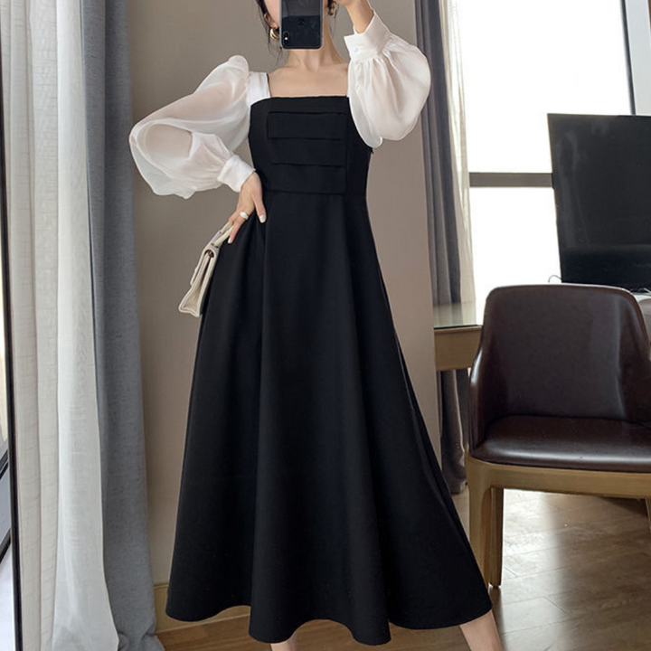 Vrouw in elegante zwarte jurk met witte pofmouwen, staand in moderne kamer. Stijlvolle mode, avondkleding, chique outfit, trendy design.