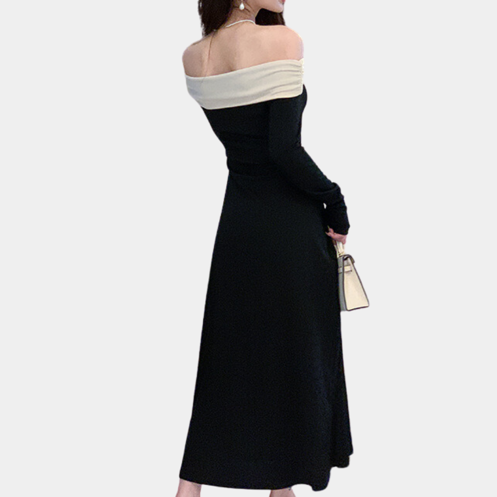 Elegante zwarte off-shoulder jurk met lange mouwen en witte kraag, gedragen door model met beige handtas. Perfect voor avondkleding en mode.