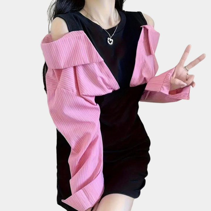 Vrouw in zwarte jurk met roze gestreepte off-shoulder blouse, maakt vredesteken. Modieuze dameskleding, trendy outfit, casual stijl.