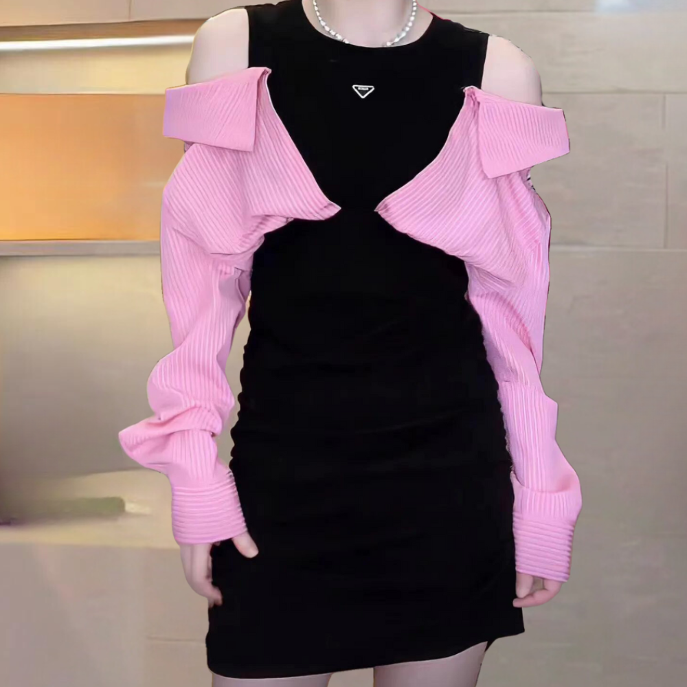 Zwarte jurk met roze ribgebreide schouderbedekking, open schouders, en parelketting. Modieuze dameskleding, trendy outfit voor avondje uit.