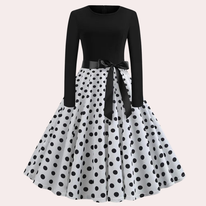 Zwart-witte polkadot jurk met lange mouwen en strik, retro stijl, elegante damesmode, perfect voor feestjes en speciale gelegenheden.