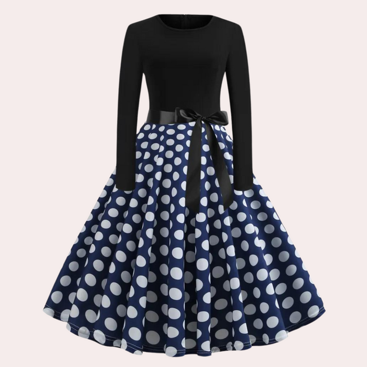 Zwart-blauwe jurk met witte stippen, lange mouwen en strikdetail. Vintage stijl, elegante damesmode, perfect voor feestelijke gelegenheden.
