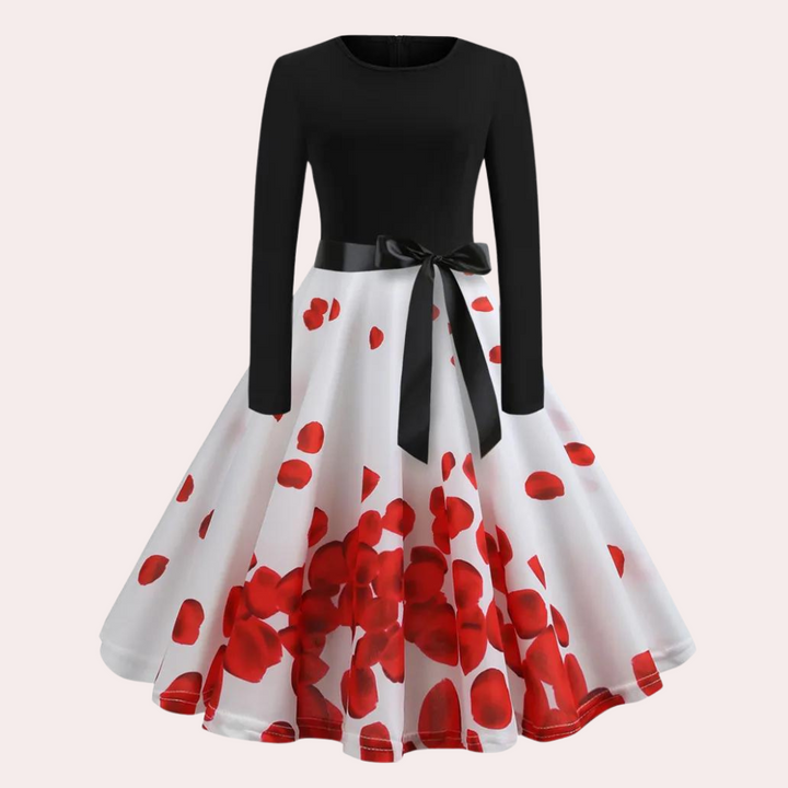 Elegante zwarte en witte jurk met lange mouwen en rode bloemenprint, strikdetail in de taille. Perfect voor feestelijke gelegenheden.