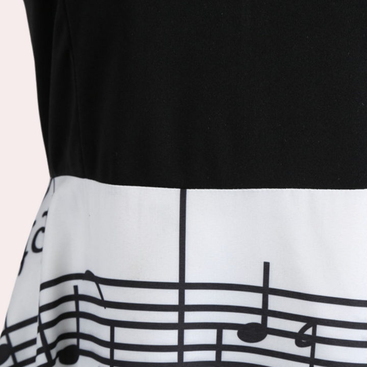 Zwart-witte jurk met muzieknotenprint, close-up van de rok. Perfect voor muziekliefhebbers, unieke mode, opvallende kledingstijl.