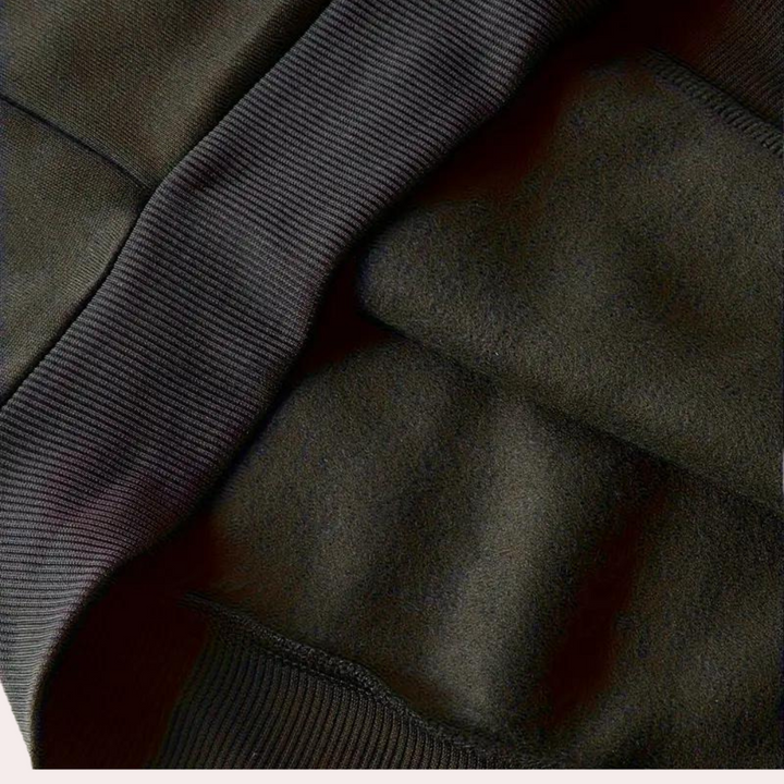 Donkergroene fleece stof close-up, zachte textuur, geribbelde rand. Perfect voor warme kleding, truien, en comfortabele wintermode.