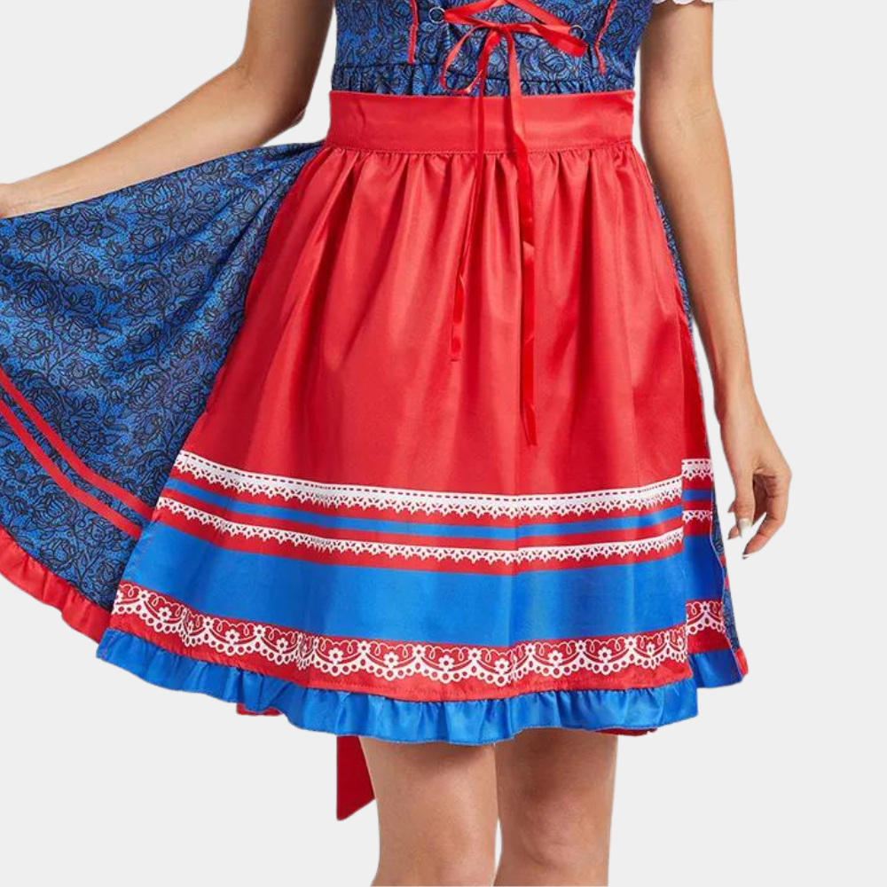 Vrouw in traditionele dirndl jurk met rood en blauw patroon, kanten details en striksluiting. Oktoberfest mode, Duitse klederdracht.