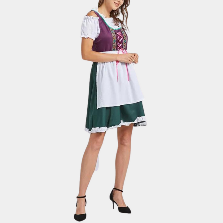 Vrouw in traditionele Duitse dirndl jurk met paarse top, groene rok en witte schort. Oktoberfest kleding, Beierse stijl, feestelijke outfit.