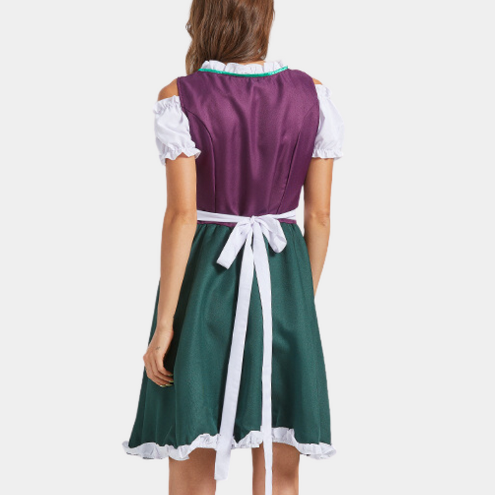 Achteraanzicht van vrouw in traditionele Duitse dirndl jurk, paars bovenstuk, groene rok, witte blouse en schort. Oktoberfest kleding.