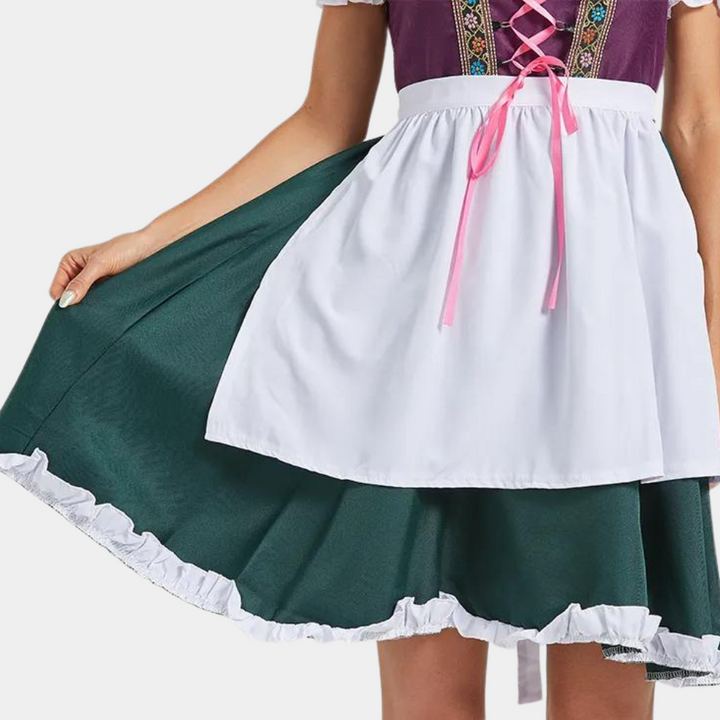 Vrouw in traditionele dirndl jurk met wit schort en groene rok, roze korset met borduursels. Oktoberfest kleding, Beierse mode.