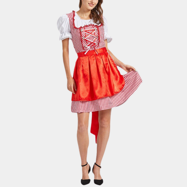 Vrouw in traditioneel Beiers dirndl-kostuum met rood-wit geruite jurk en schort, perfect voor Oktoberfest. Duitse folklore mode.