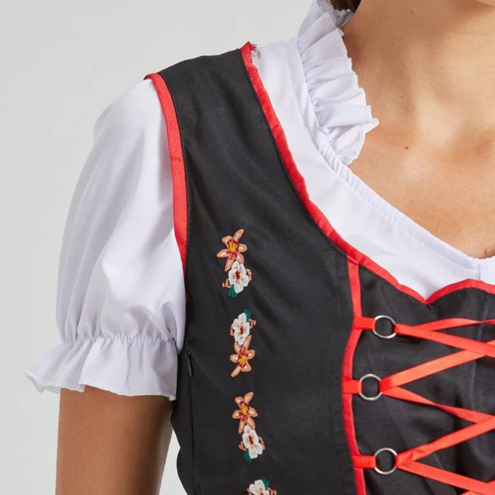 Zwarte dirndl met rode biezen, witte blouse en bloemenborduursel. Traditionele Beierse kleding, perfect voor Oktoberfest en themafeesten.