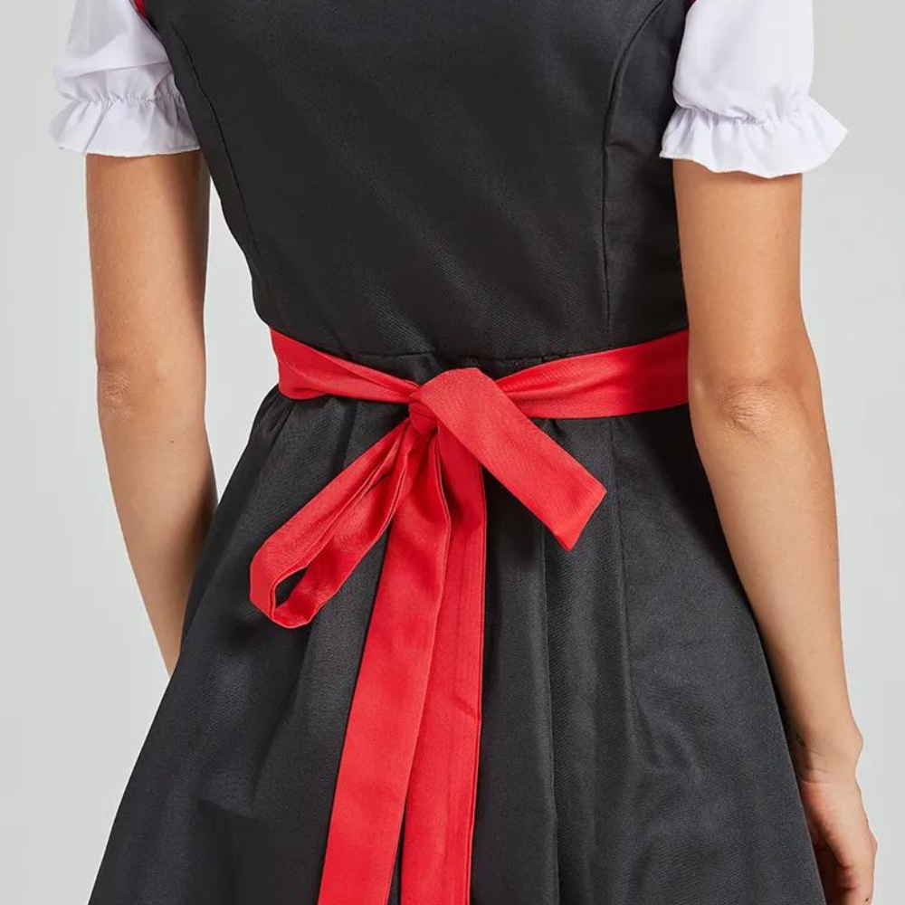 Zwarte jurk met rode strik en witte pofmouwen, achteraanzicht. Traditionele dirndl-stijl, perfect voor Oktoberfest of feestelijke gelegenheden.