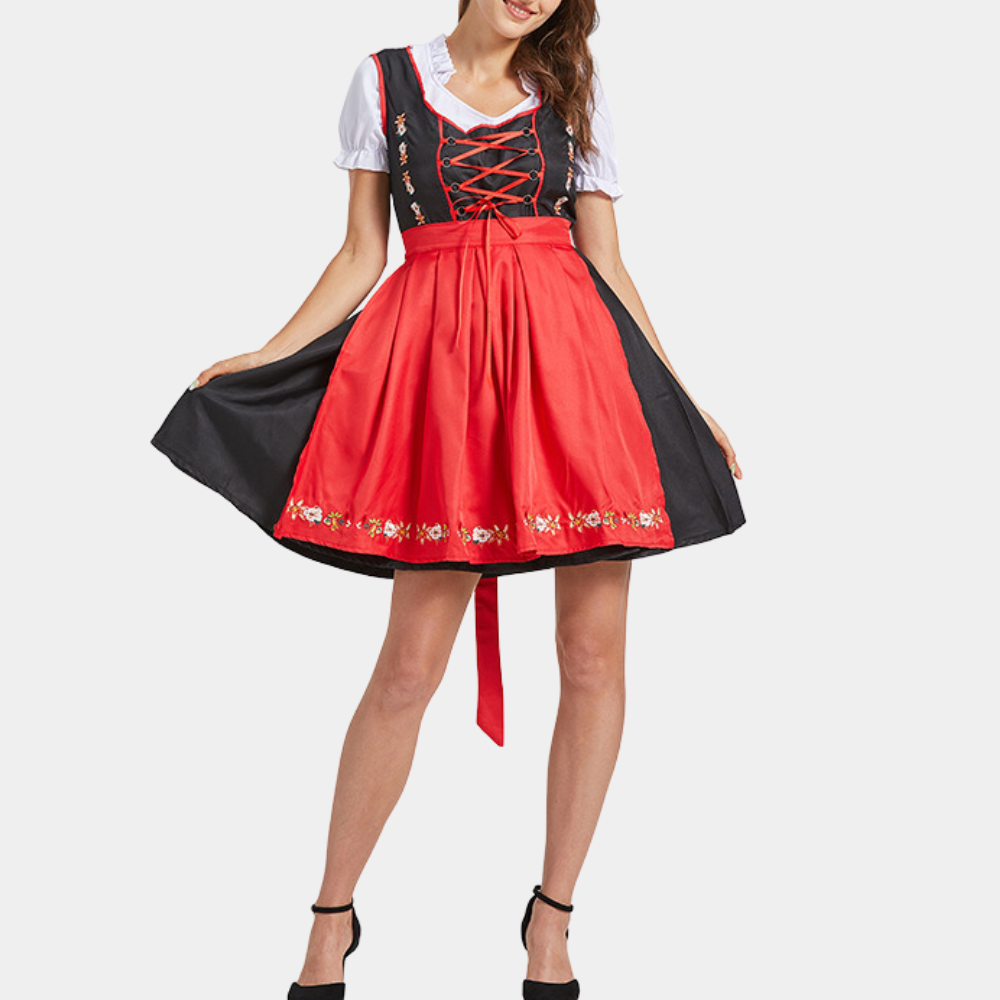 Vrouw in traditionele rode dirndl jurk met geborduurde details, zwarte schort en witte blouse. Oktoberfest kleding, Duitse folklore mode.
