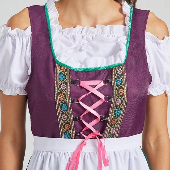 Paarse dirndl jurk met witte blouse, roze linten en kleurrijke borduursels. Traditionele Beierse kleding, perfect voor Oktoberfest.