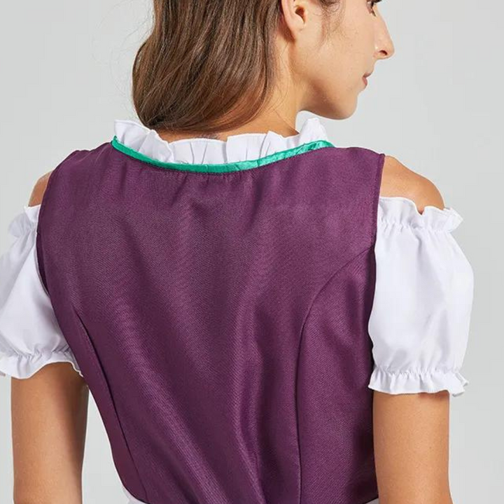 Vrouw in traditionele paarse dirndl met witte blouse en groene accenten, gezien van achteren. Oktoberfest mode, Beierse klederdracht.