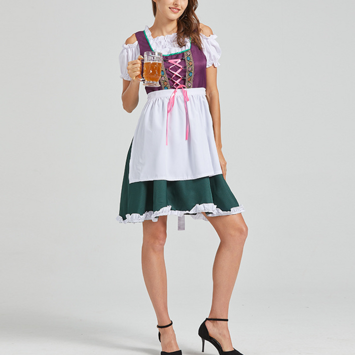 Vrouw in traditioneel Beiers dirndl-kostuum met paarse top en groene rok, houdt een bierpul vast. Oktoberfest kleding, Duitse folklore.