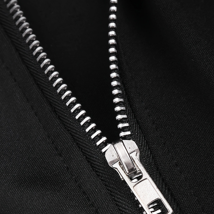 Zilverkleurige metalen ritssluiting op zwarte stof, close-up. Hoogwaardige rits, modeaccessoire, textiel, kledingdetail.