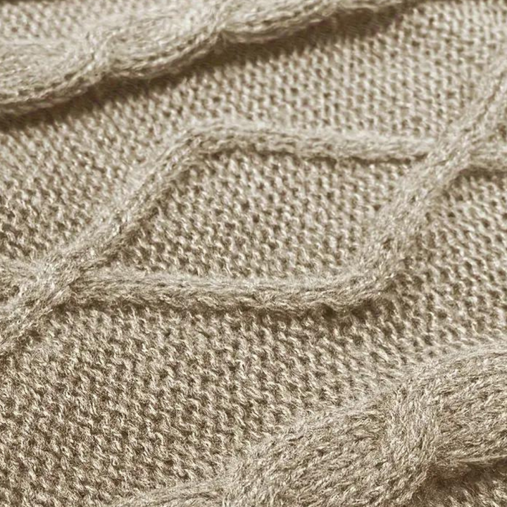 Beige gebreide trui met kabelpatroon, close-up. Zachte woltextuur, modieus en warm. Perfect voor herfst- en winterkleding.