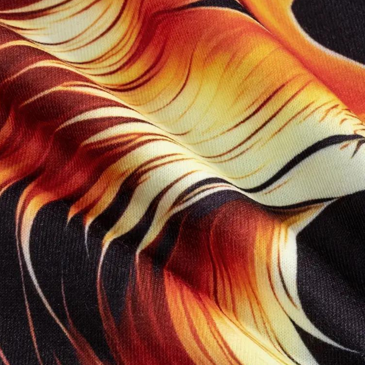 Close-up van kleurrijke stof met vlammenpatroon, levendige oranje en gele tinten op zwarte achtergrond, ideaal voor mode en interieurontwerp.