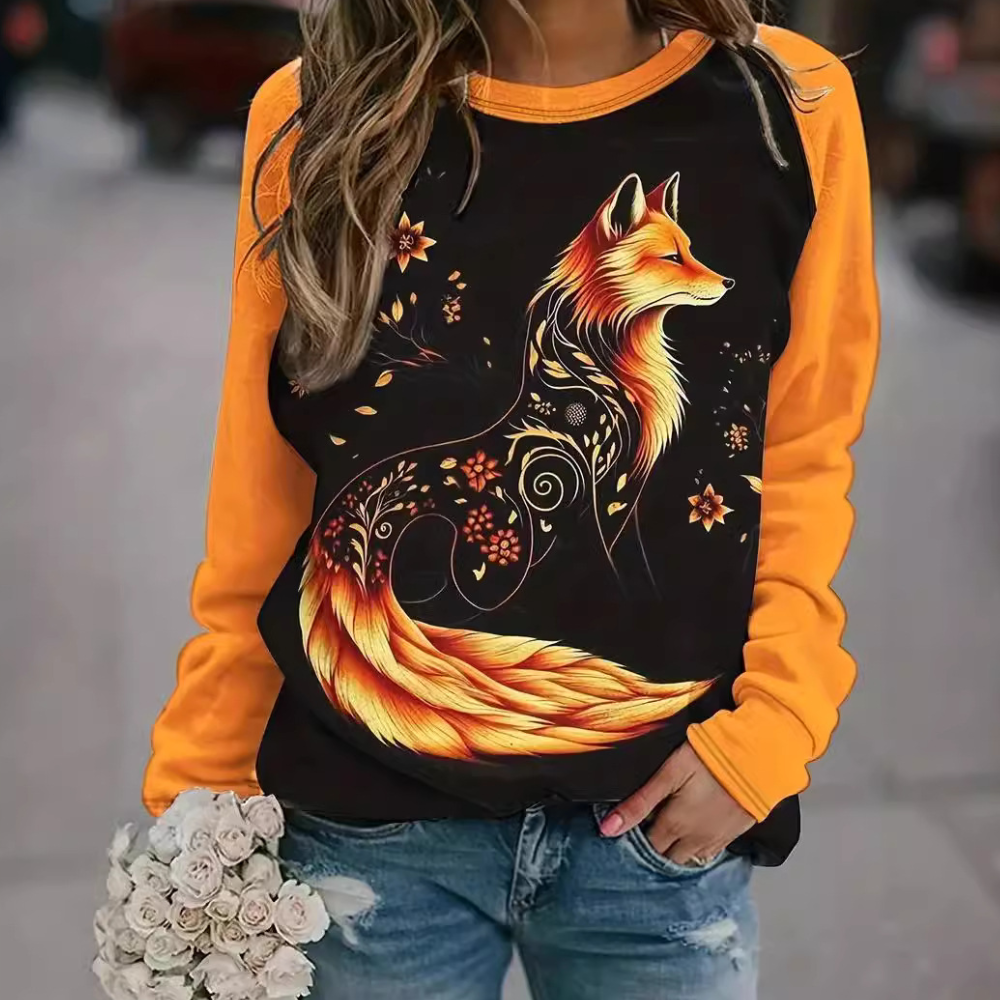 Vrouw draagt oranje trui met artistieke vosprint, bloemenmotief. Modieuze herfstkleding, casual stijl, perfect voor dierenliefhebbers.