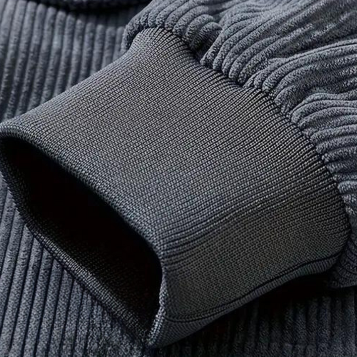 Donkergrijze ribgebreide trui met geribbelde manchetten, close-up. Hoogwaardige stof, comfortabele pasvorm, modieuze herenkleding.