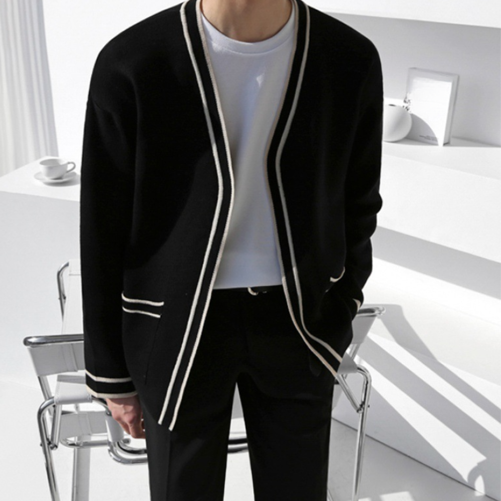 Zwarte herenblazer met witte biezen, gedragen over een wit T-shirt. Moderne, minimalistische stijl. Geschikt voor zakelijke en casual gelegenheden.